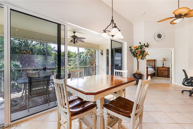 dining space featuring a ceiling fan, light tile patterned floors, a towering ceiling, and baseboards