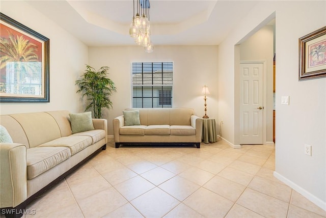 living area featuring a tray ceiling, light tile patterned flooring, and baseboards