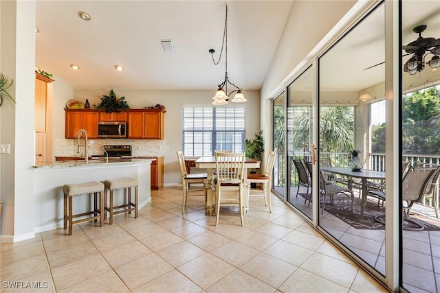 dining space with healthy amount of natural light, vaulted ceiling, light tile patterned flooring, a chandelier, and baseboards
