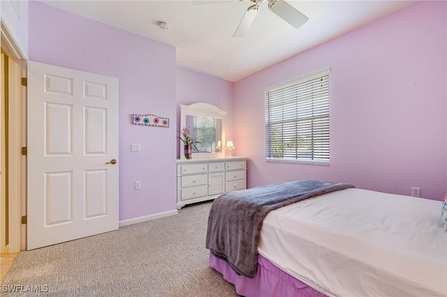 bedroom featuring light colored carpet, a ceiling fan, and baseboards