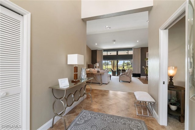hallway with baseboards, vaulted ceiling, and tile patterned flooring