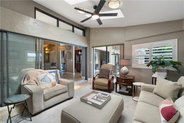 living room featuring a ceiling fan and vaulted ceiling with skylight