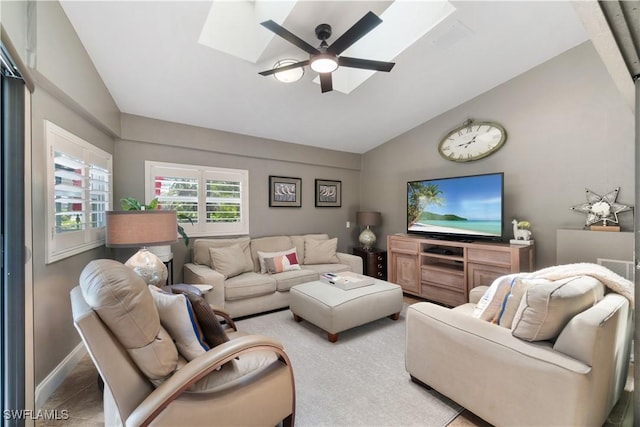 living room with baseboards, lofted ceiling with skylight, and a ceiling fan