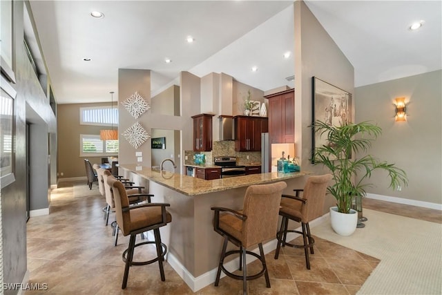 kitchen featuring decorative backsplash, high vaulted ceiling, appliances with stainless steel finishes, a sink, and a breakfast bar area