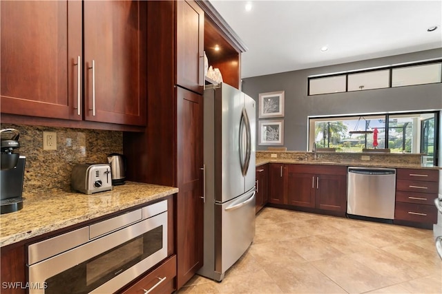 kitchen featuring light stone counters, a sink, tasteful backsplash, stainless steel appliances, and recessed lighting