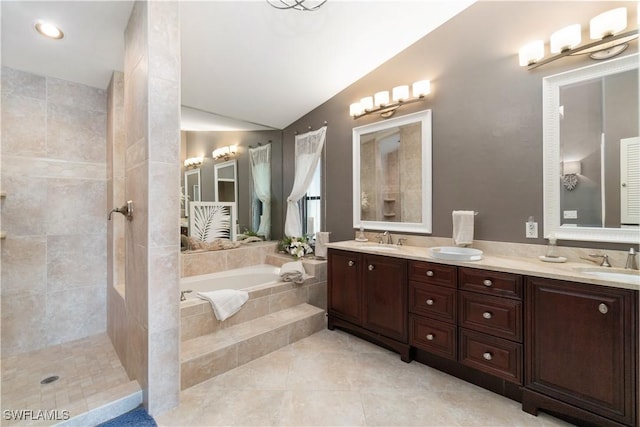 full bath with a bath, lofted ceiling, a sink, and double vanity