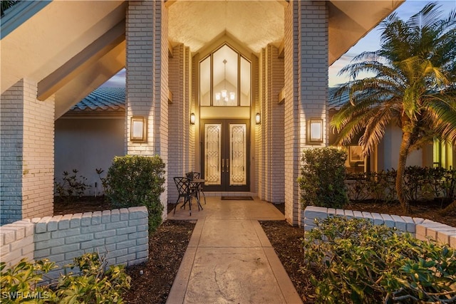 view of exterior entry featuring french doors, brick siding, and stucco siding