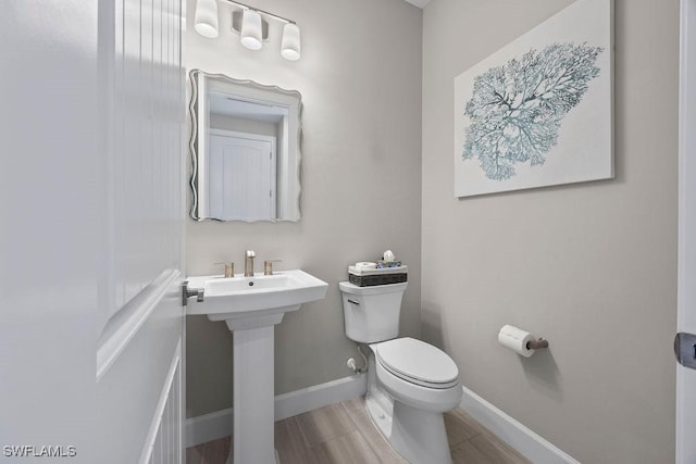 half bath featuring baseboards and toilet