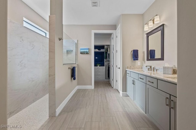bathroom with visible vents, a walk in closet, vanity, and a walk in shower