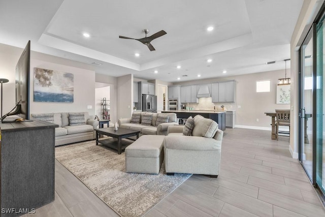 living room with baseboards, a raised ceiling, ceiling fan, and wood tiled floor