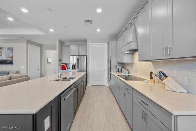 kitchen with visible vents, premium range hood, gray cabinetry, stainless steel appliances, and a sink
