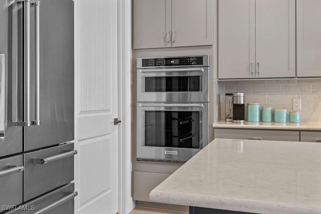 kitchen with tasteful backsplash, appliances with stainless steel finishes, and light stone counters