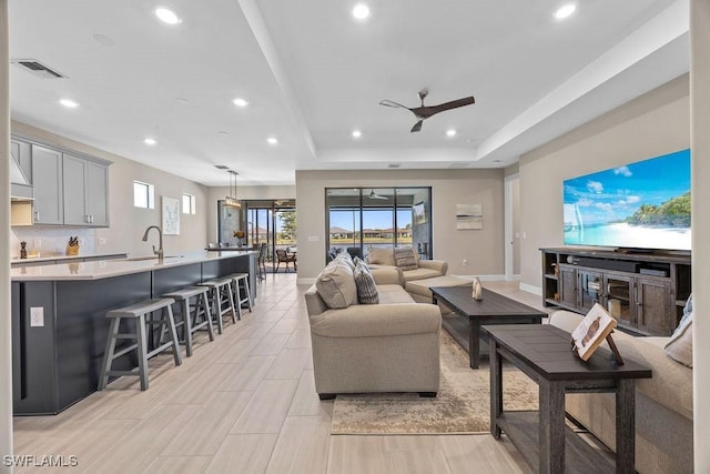 living room with visible vents, a ceiling fan, recessed lighting, baseboards, and a raised ceiling