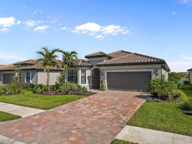 mediterranean / spanish-style home featuring stucco siding, a tile roof, decorative driveway, and a garage