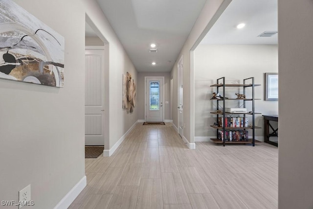 hallway featuring light wood-type flooring, visible vents, baseboards, and recessed lighting