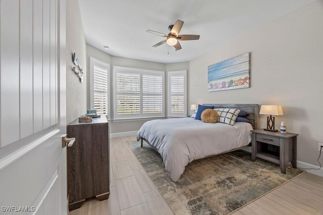 bedroom featuring a ceiling fan, baseboards, and wood tiled floor