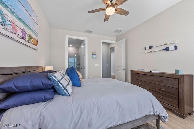 bedroom with light wood-type flooring, visible vents, ensuite bath, and ceiling fan