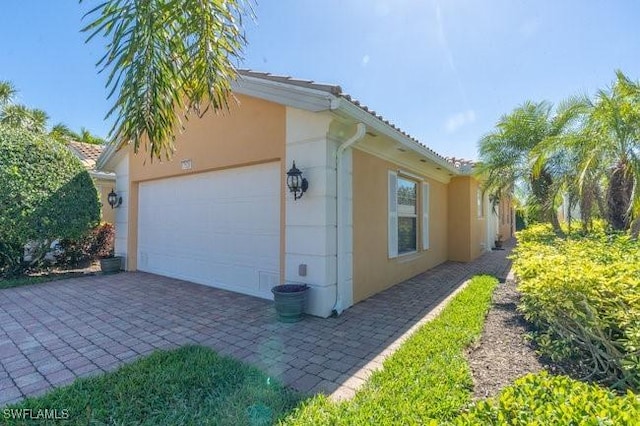 7520 Firenze Ln, Naples, FL 34114 - view of home's exterior with stucco siding, decorative driveway, and a garage