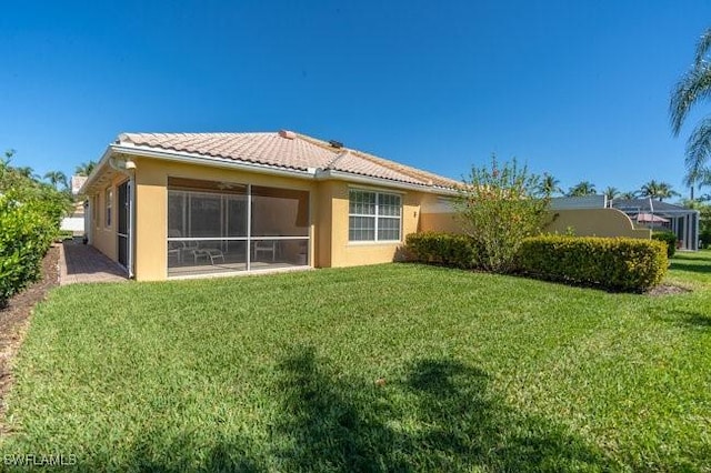 7520 Firenze Ln, Naples, FL 34114 - rear view of property with a tiled roof, a lawn, a sunroom, and stucco siding