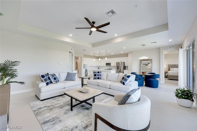 living area featuring visible vents, ceiling fan, and a tray ceiling