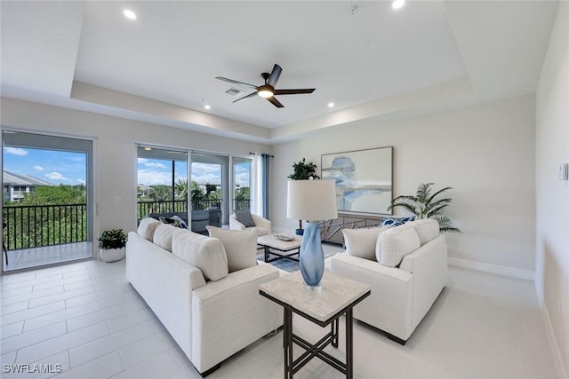 living room featuring baseboards, a raised ceiling, and ceiling fan