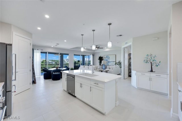 kitchen featuring an island with sink, stainless steel appliances, a sink, white cabinetry, and open floor plan