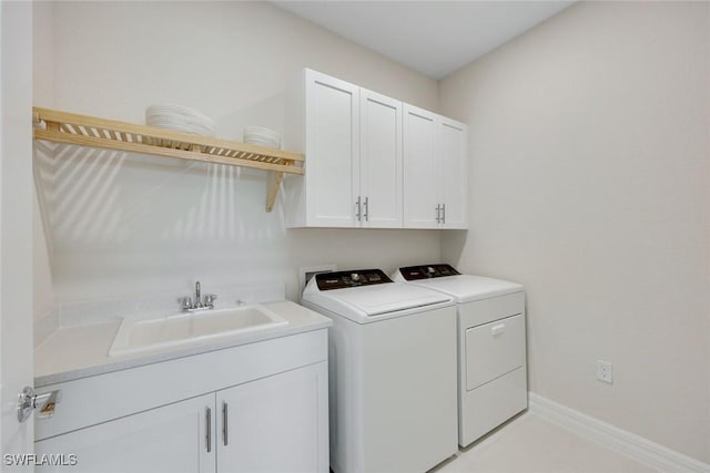 laundry room with washing machine and dryer, cabinet space, baseboards, and a sink