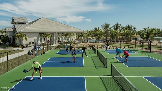 view of tennis court featuring community basketball court and fence