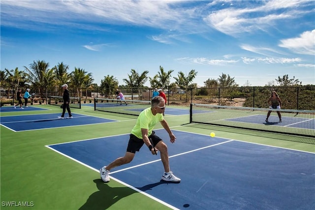 view of tennis court featuring community basketball court and fence