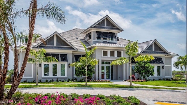 view of front of property with a front yard, a standing seam roof, stucco siding, french doors, and metal roof