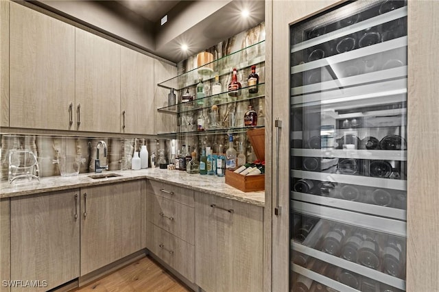 interior space featuring a sink, wine cooler, light wood-style floors, and bar