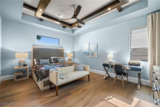 bedroom with baseboards, a tray ceiling, visible vents, and light wood-type flooring