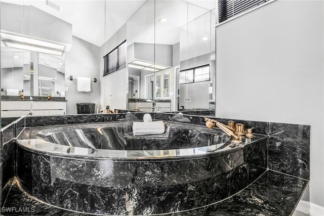 full bath with vanity, a garden tub, and visible vents