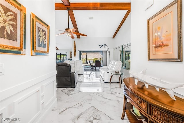 hallway featuring marble finish floor, vaulted ceiling with beams, and a wainscoted wall