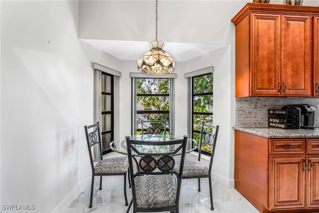 dining room with an inviting chandelier, marble finish floor, and baseboards