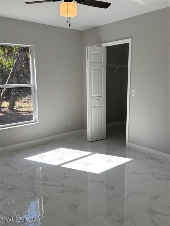 4430 18th Ave NE, Naples, FL 34120 - unfurnished bedroom featuring a closet, marble finish floor, baseboards, and ceiling fan