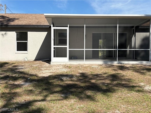 4430 18th Ave NE, Naples, FL 34120 - rear view of house with stucco siding, a shingled roof, a lawn, and a sunroom