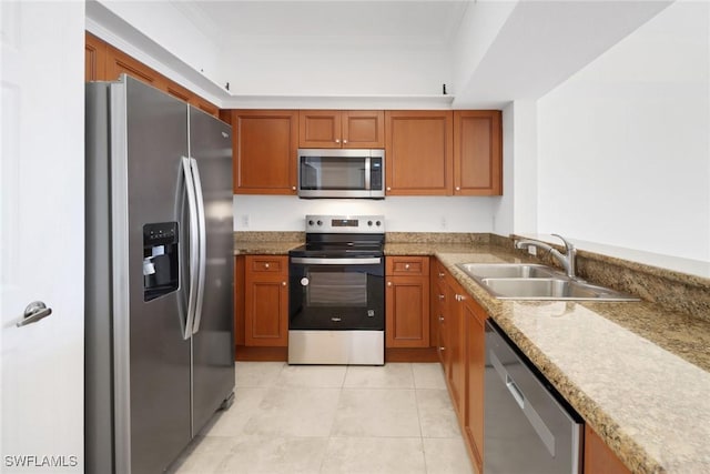 kitchen featuring a sink, appliances with stainless steel finishes, brown cabinetry, and crown molding