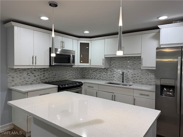 kitchen featuring white cabinetry, pendant lighting, stainless steel appliances, and a sink