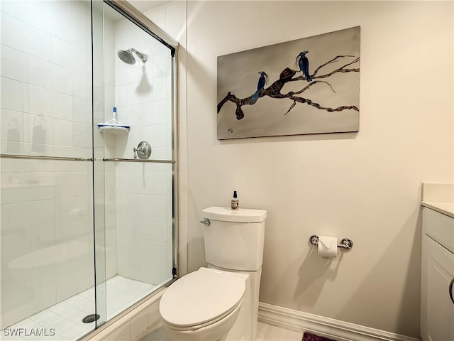 bathroom featuring vanity, toilet, baseboards, and a stall shower