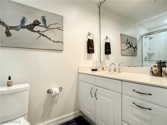 bathroom featuring a shower with door, toilet, vanity, and baseboards
