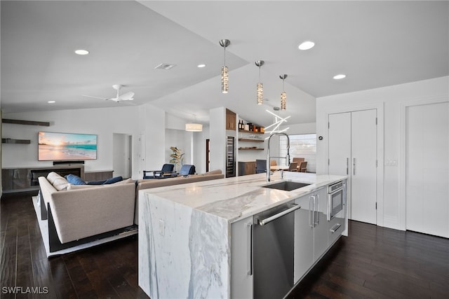 kitchen featuring stainless steel dishwasher, a sink, dark wood finished floors, lofted ceiling, and pendant lighting