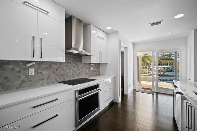 kitchen with black electric cooktop, visible vents, wall chimney range hood, modern cabinets, and stainless steel oven