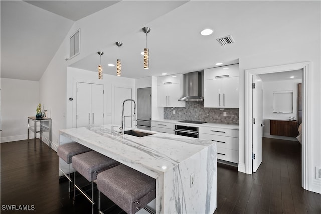 kitchen featuring wall chimney range hood, a sink, modern cabinets, stainless steel oven, and visible vents