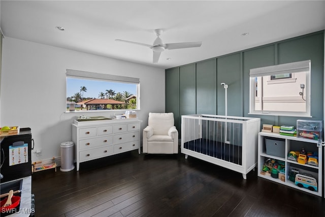 bedroom featuring ceiling fan, wood finished floors, and a crib