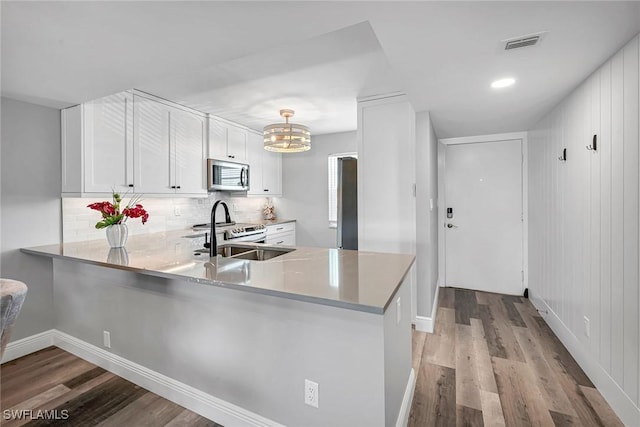 4200 Belair Ln Unit 303, Naples, FL 34103 - kitchen featuring light wood-style flooring, a sink, appliances with stainless steel finishes, white cabinets, and decorative backsplash