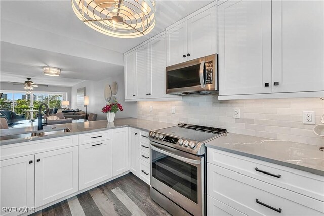 4200 Belair Ln Unit 303, Naples, FL 34103 - kitchen featuring dark wood finished floors, a sink, decorative backsplash, stainless steel appliances, and white cabinetry