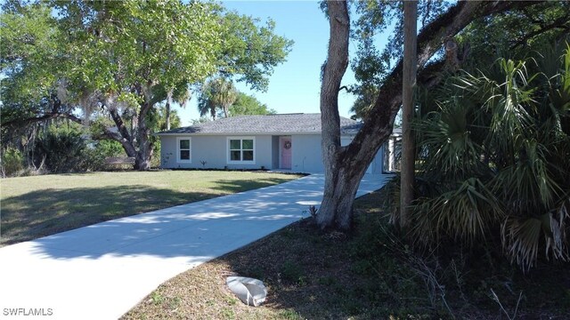 ranch-style home with stucco siding, driveway, and a front lawn