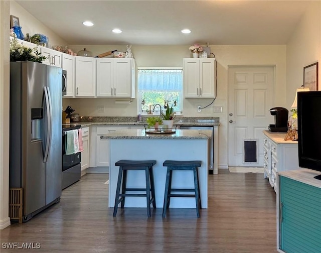 kitchen with appliances with stainless steel finishes, a breakfast bar, and white cabinets