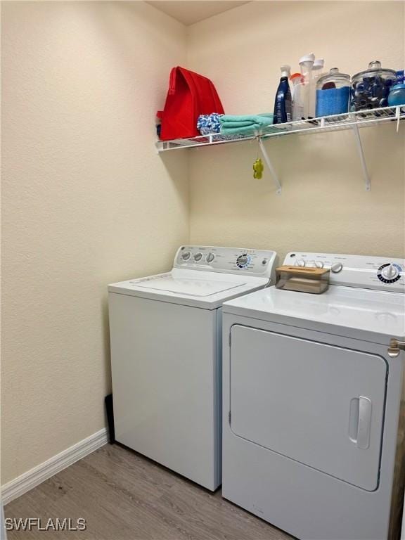 laundry room featuring baseboards, light wood-style floors, laundry area, and washing machine and clothes dryer